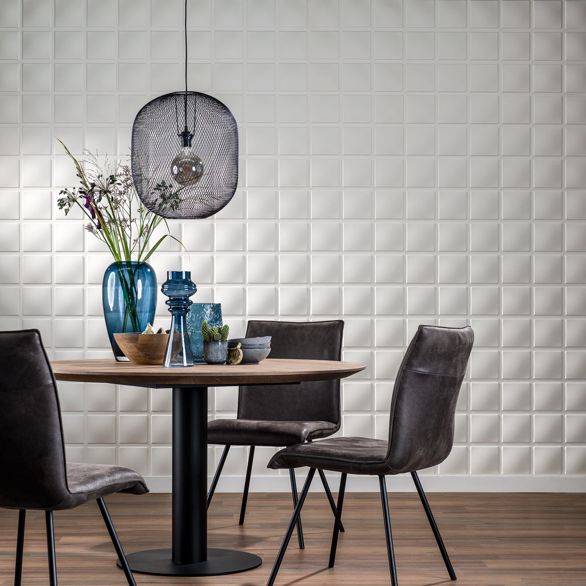 Dining area with a table and chairs against a 3D wall panel 'Cubes'.