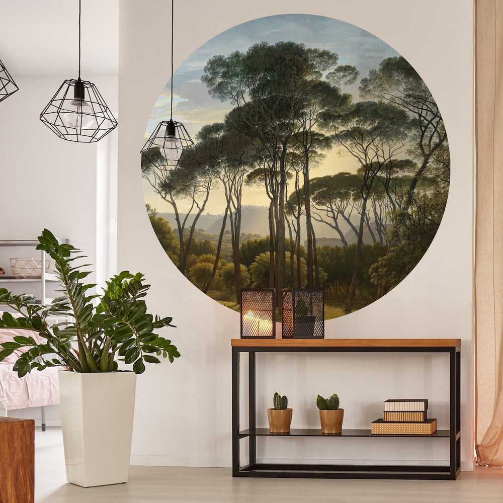 Modern interior with a Wallpaper circle of Pine trees in Italy, a plant, and a shelf with decorative items.